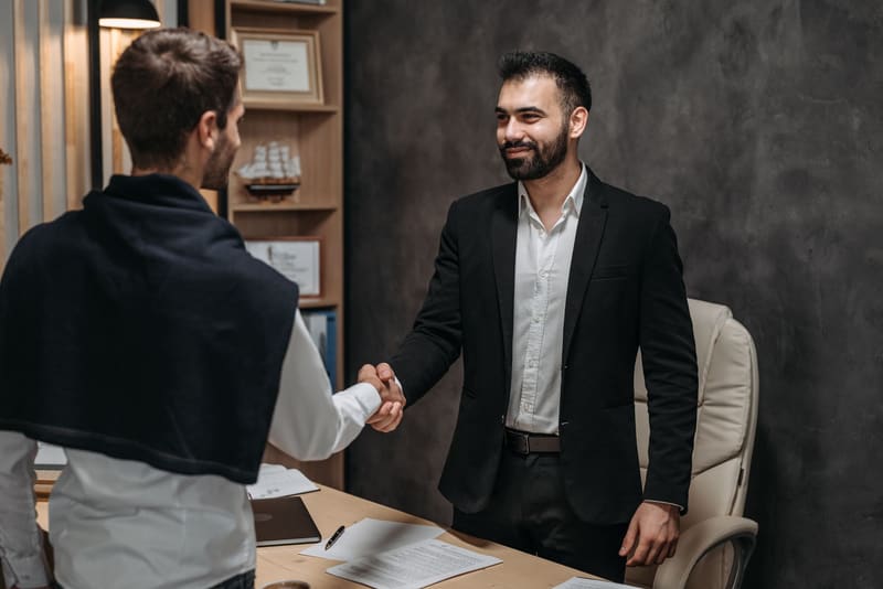 Abogado estrechando la mano a un cliente en su despacho tras encontrarle en Google