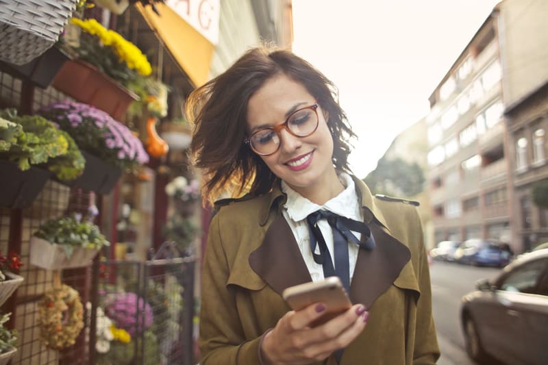 Mujer junto a una floristería leyendo en el móvil la respuesta de las AI Overviews de Google
