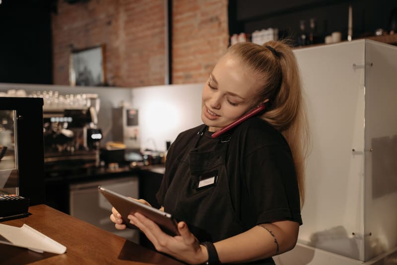 Camarera de una cafetería atiende en el móvil la llamada de un cliente que llega desde su anuncio, así funciona Google Ads