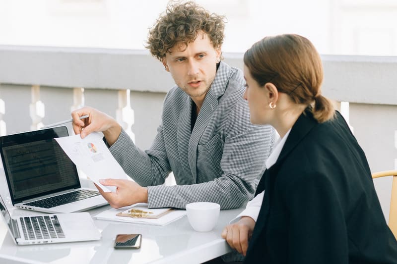 Consultor SEO local explicando un informe a la dueña de un negocio en una terraza