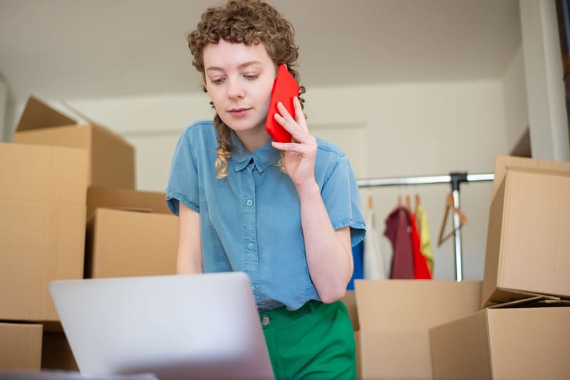 Dueña de una pequeña tienda online llama a un cliente mientras revisa su ficha en el CRM del portátil