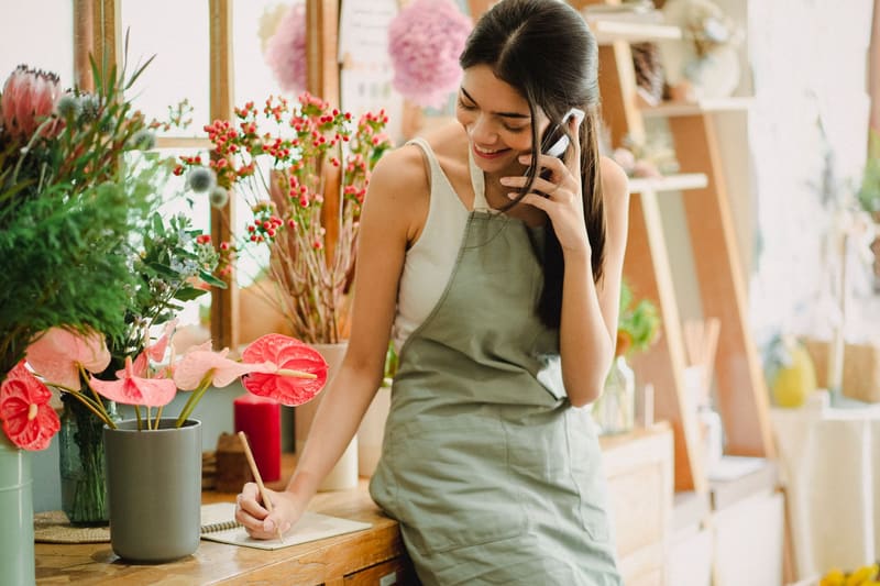 Florista atendiendo la llamada de una clienta en su tienda
