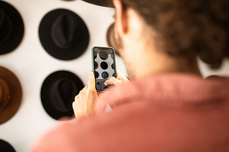 Dueño de una sombrerería haciendo fotos de sus productos con el móvil para el Perfil de Empresa de Google