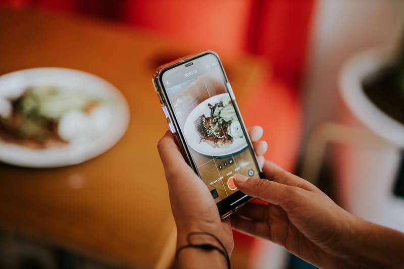 Mano haciendo con el móvil una foto de un plato para la ficha de Google del restaurante