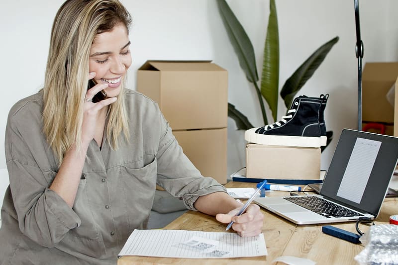 Dueña de un negocio atendiendo la llamada de un cliente y apuntándola, uno de los KPI de marketing digital que importan