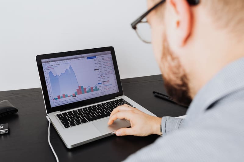 Hombre revisando en el portátil las métricas de su negocio para elegir los KPI de marketing digital del mes