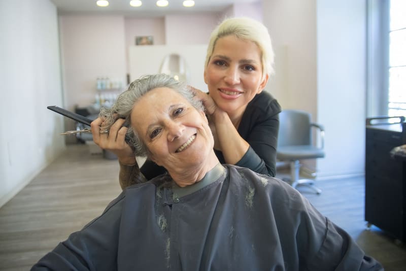Peluquera sonriendo junto a su clienta en el salón, un ejemplo de marca personal en un negocio local