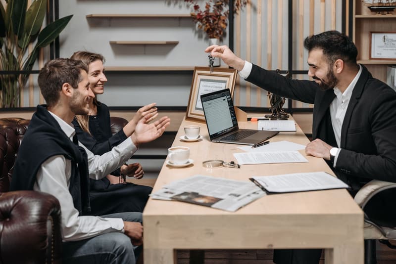 Agente inmobiliario entregando las llaves a una pareja en su oficina, el final de un buen marketing para inmobiliarias
