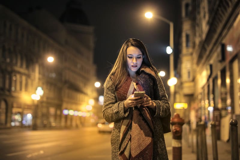 Mujer buscando de noche en el móvil un negocio que no aparece en Google Maps