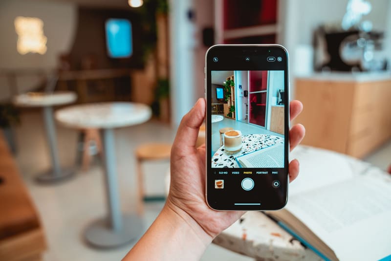 Móvil haciendo una foto del interior de una cafetería para optimizar la ficha de Google del negocio