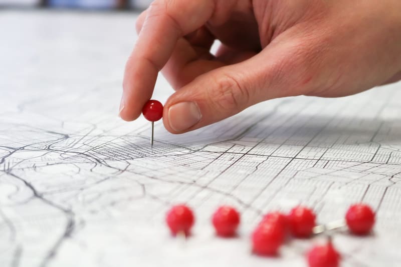 Mano clavando una chincheta roja en un mapa: así se pone un negocio en Google Maps