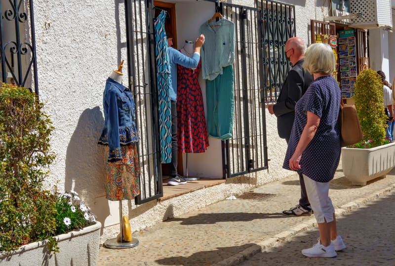 Clientes mirando el escaparate de una tienda de ropa en una calle de pueblo, el tipo de negocio que vive del SEO local